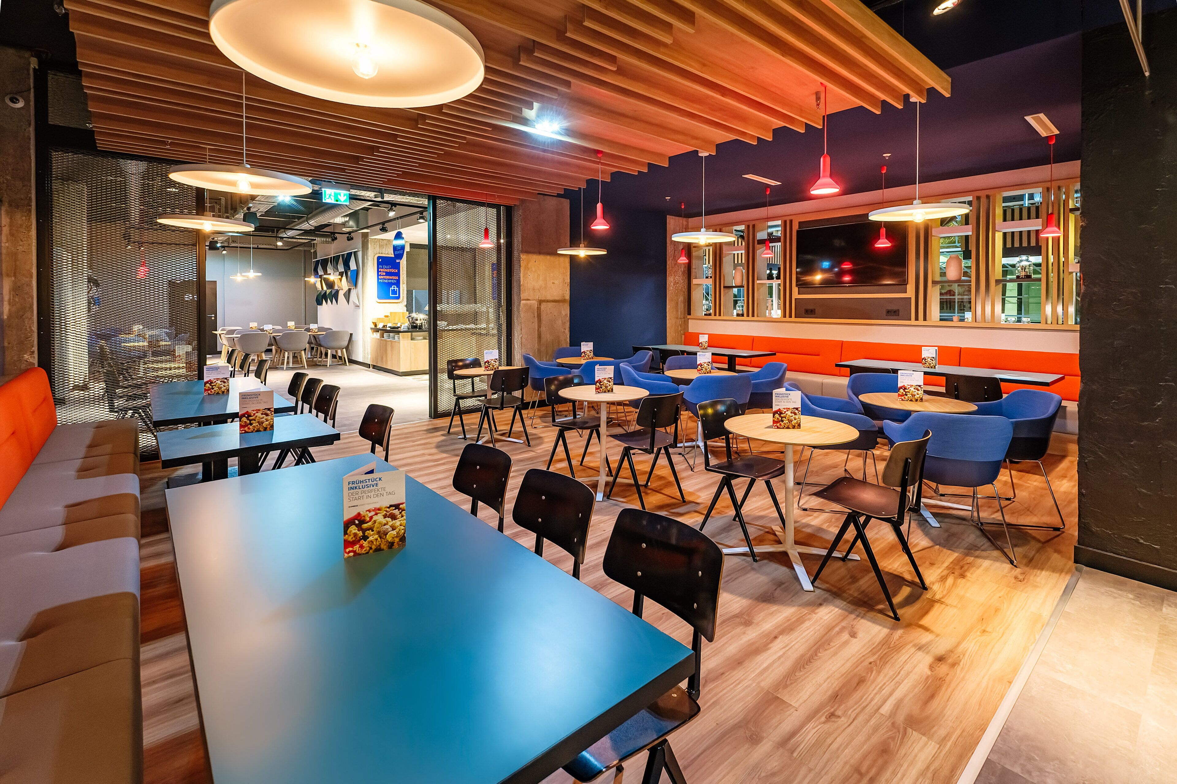 A modern dining area with tables, chairs, and a mix of seating options including a bench and booths.