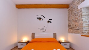 A bedroom with a large bed, two bedside tables, and a stone wall. - House 2176/55604 (Istria - Debeljuhi), 19000m from the beach (Debeljuhi)