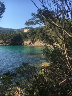 Un paisaje costero con aguas turquesas cristalinas, acantilados rocosos y abundante vegetación.