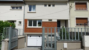 En bostadsbyggnad med en grind vid ingången, ett garage och en liten veranda.