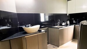 Una cocina moderna con un lavamanos grande de color blanco, encimeras oscuras y armarios de madera.
