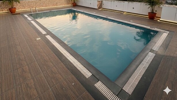Piscina rectangular en una terraza en la azotea con plantas en macetas y vista al horizonte urbano al atardecer.
