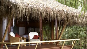 A thatched-roof outdoor seating area with wicker furniture and a wooden deck. - One Myanmar Resort Putao (Putao)