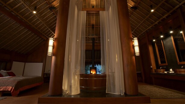 A cozy room with a bed, a wooden ceiling, and a fireplace. - One Myanmar Resort Putao (Putao)