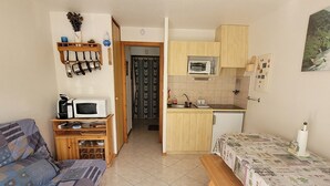 A compact living space with a kitchenette, a dining area, and a sofa.