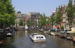 Een gracht met een boot genaamd 'Holland International' en gebouwen met rode vlaggen.