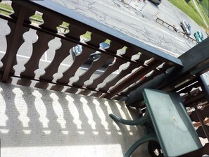 A metal railing with a decorative pattern, a concrete floor, and a green metal chair.