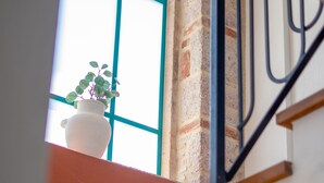 Una escalera con una pared blanca, una pared de ladrillo y una ventana con una planta en el alféizar.