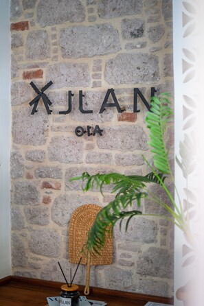 A stone wall with a sign reading "XLAN OLA". - Ajlan Oia (Ayvalik)