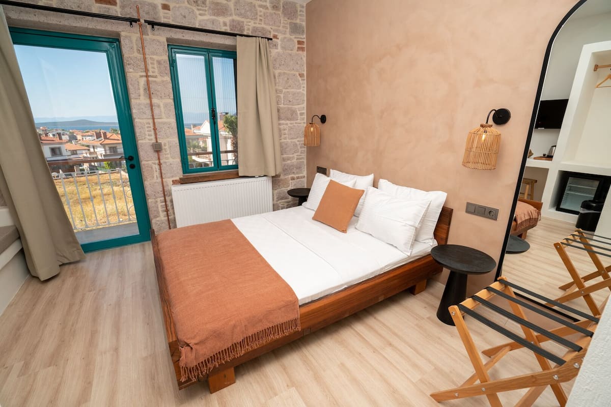 A bedroom with a wooden bed, a view of the city, a large mirror, and a hanging light fixture.