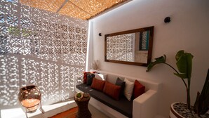 Una sala moderna con un sofá blanco, pared con estampado y una planta en maceta.