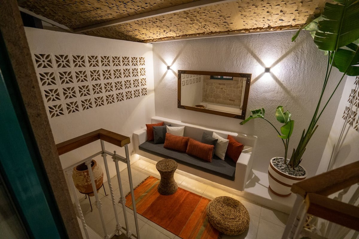 A modern interior with a white sofa, patterned wall, and a potted plant.