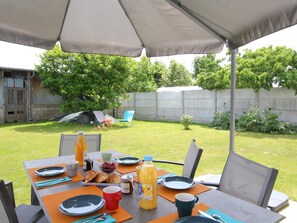 Un espace de restauration en plein air avec une table dressée pour le petit-déjeuner, comprenant des croissants, du jus de fruits et du café.