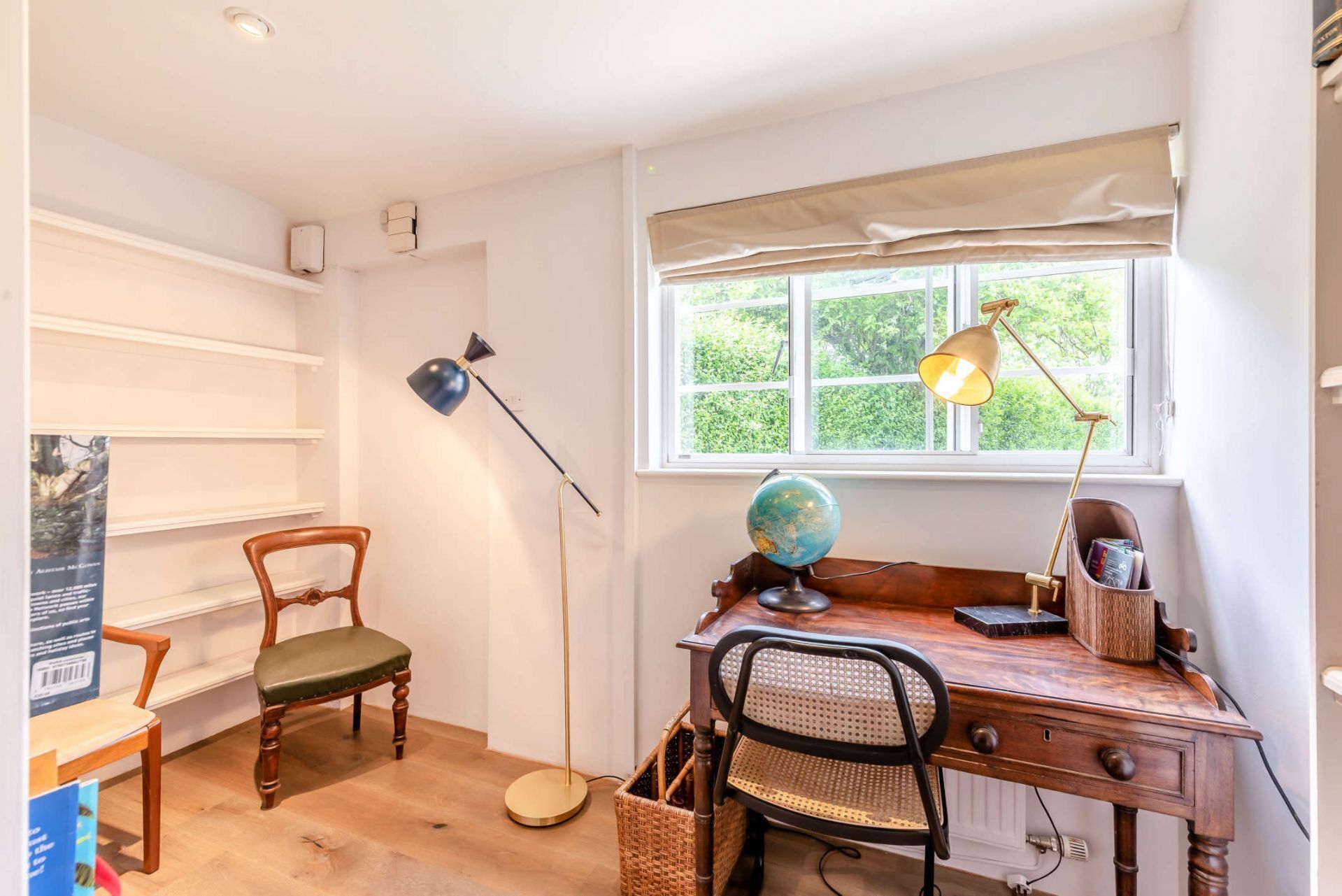 Une salle d’étude équipée d’un bureau en bois, de deux chaises, d’un globe terrestre et d’une lampe.