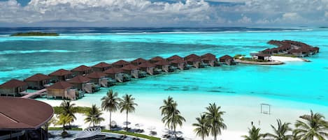 A resort with overwater bungalows connected by walkways, a pool area, and a beach.