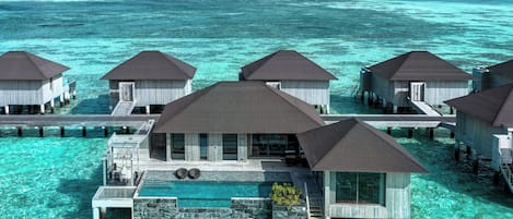 Cabañas sobre el agua con aguas azules cristalinas a su alrededor.