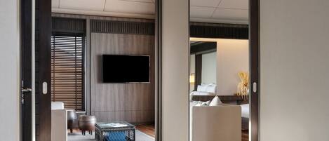 A modern hotel room with a glass floor, wooden ceiling, and a flat-screen TV mounted on the wall.