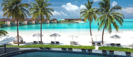 A resort with a swimming pool, beach, and overwater bungalows.