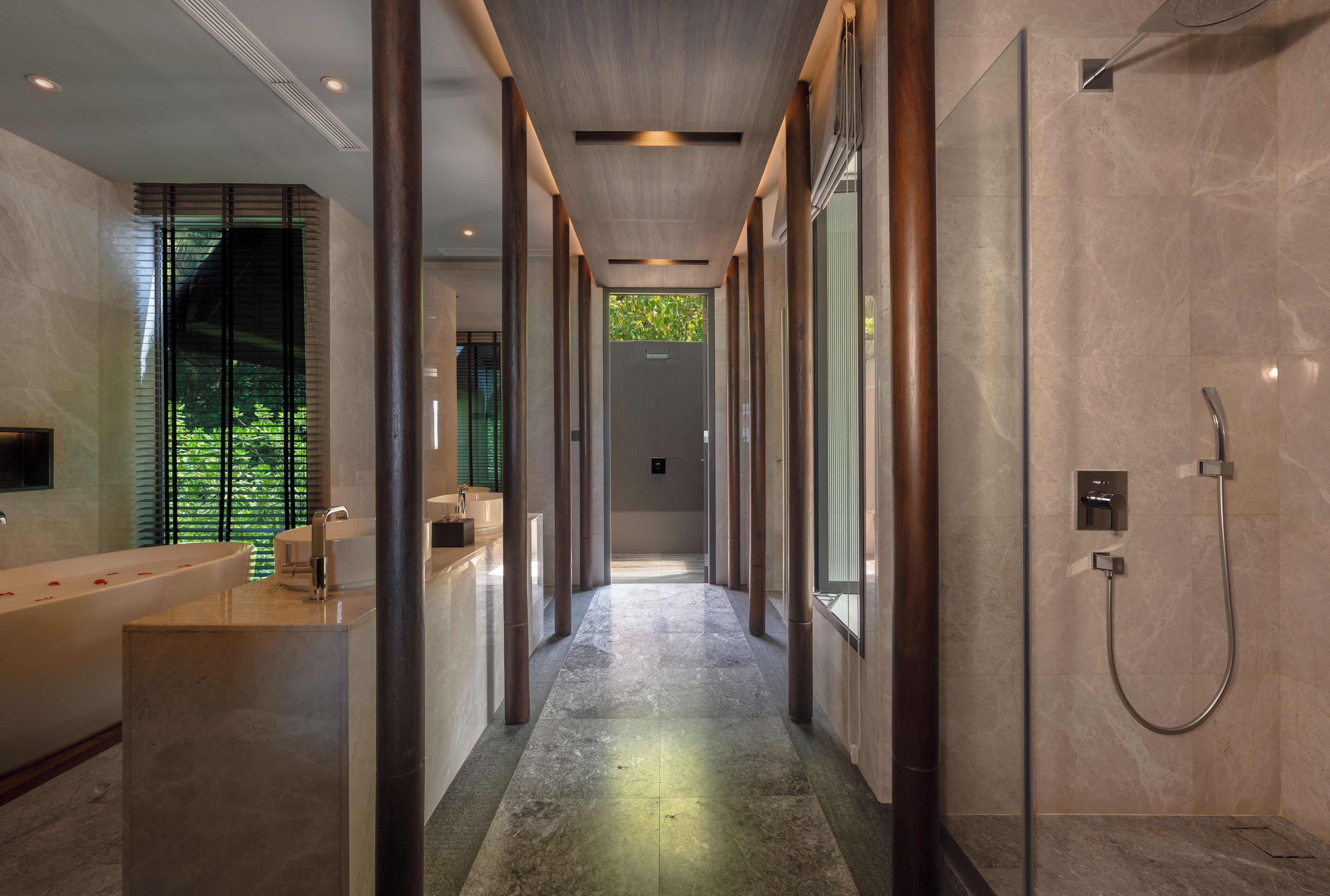 A modern bathroom with a long corridor, a bathtub, a shower area, and a large window with greenery outside.
