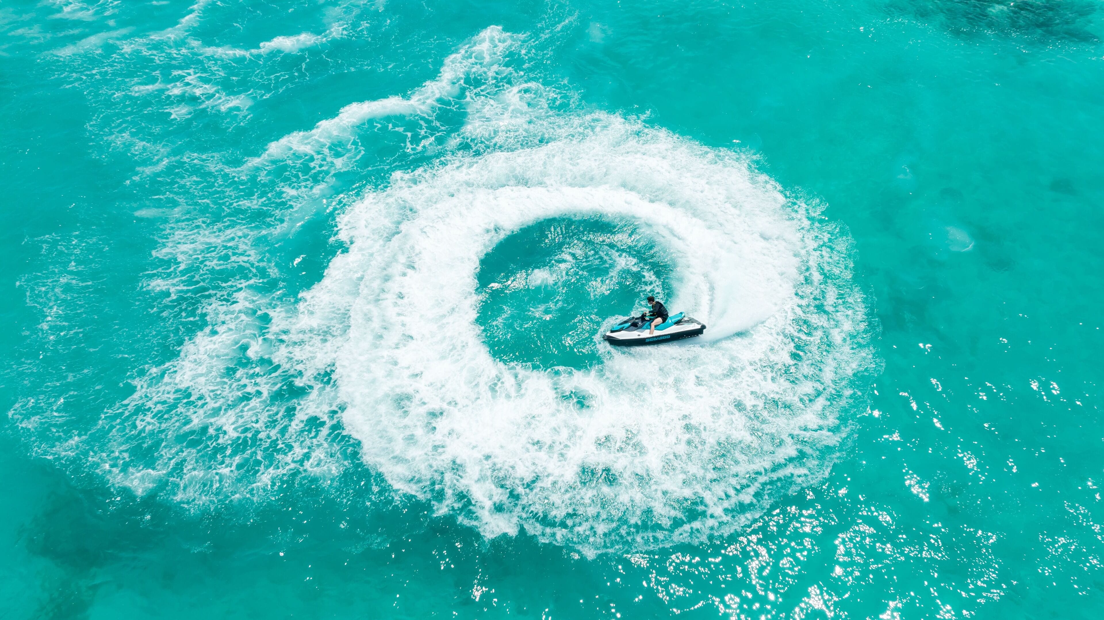 A jet ski creating a circular wake in turquoise water.