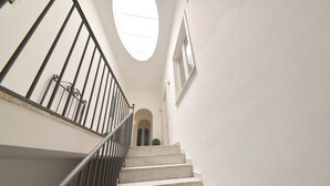 A staircase with a metal railing, white walls, and a skylight. - Queen Suite (Forio)