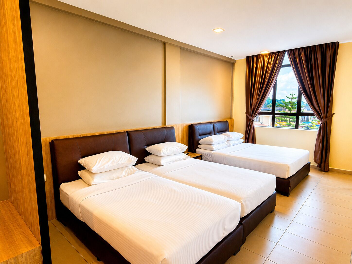 A hotel room with two beds, a large window with curtains, and a view of the outside.