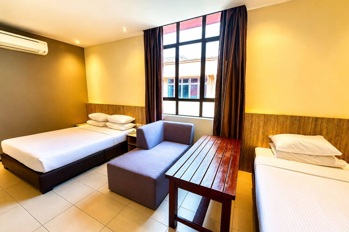 Una habitación de hotel con dos camas, un sofá, una mesa de madera y una ventana con cortinas.