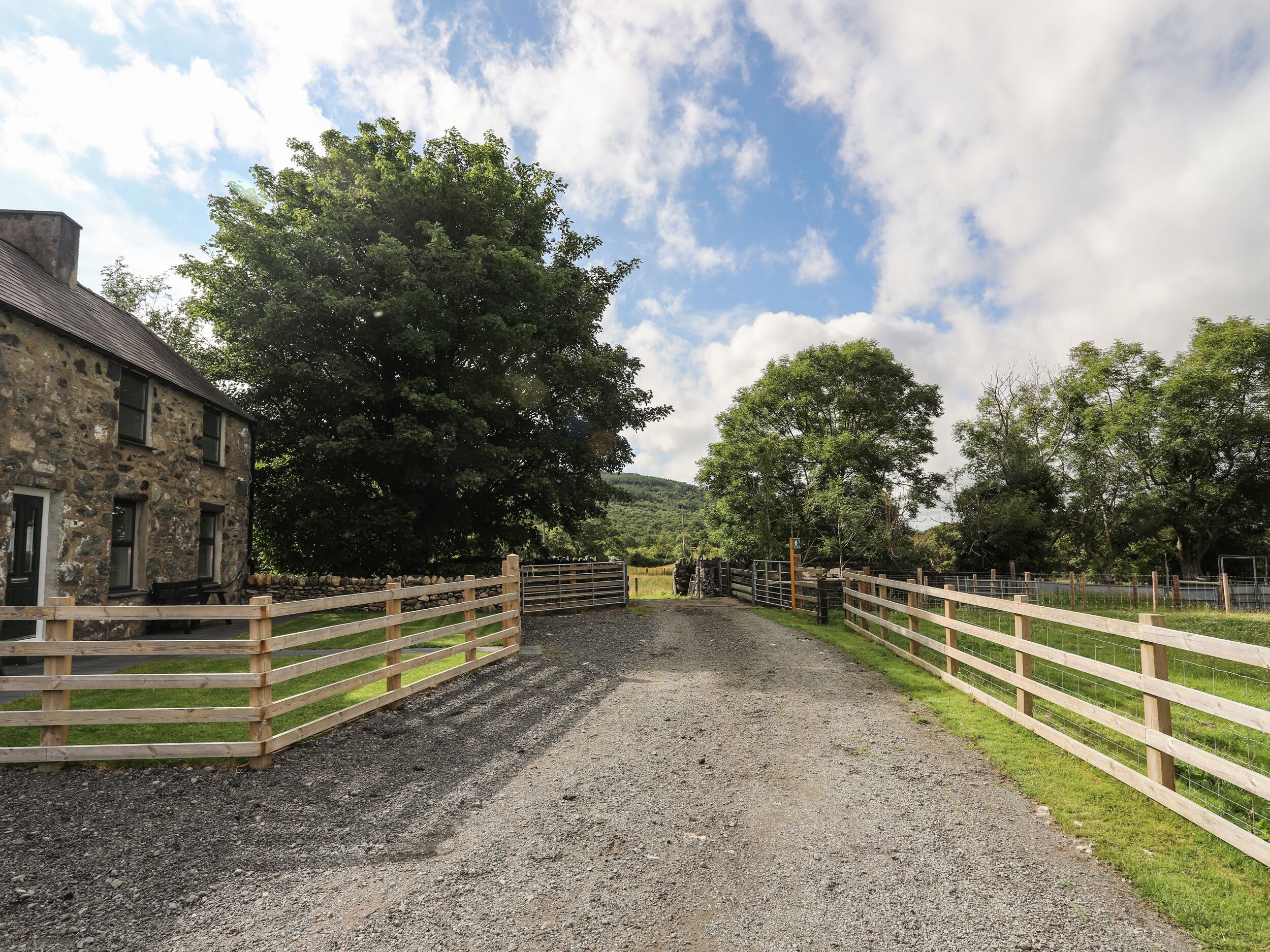 A gravel path leading to a stone building with a wooden fence.
