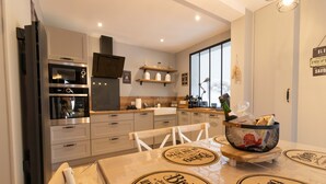 Una cocina moderna con electrodomésticos integrados, encimeras de madera y un comedor con una mesa preparada para dos personas.
