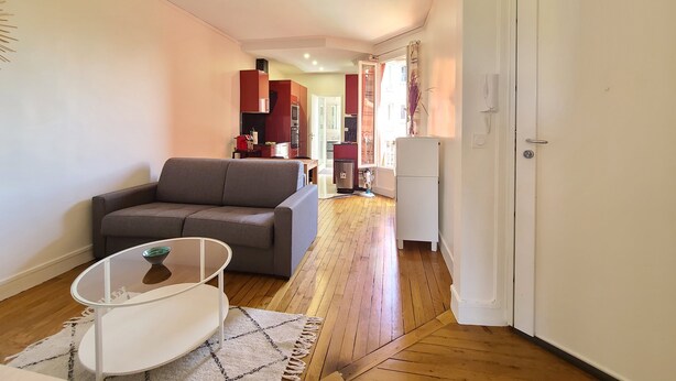 Ein modernes Wohnzimmer mit grauem Sofa, einem Glastisch und Holzboden.