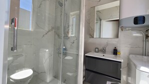 Ein modernes Badezimmer mit Duschkabine, Toilette, Waschbecken und Spiegel.