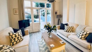 A living room with two sofas, a coffee table, a TV, and a window with curtains.