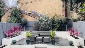 A backyard with a patio, potted plants, and a brick wall.
