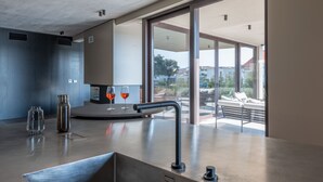 Une cuisine moderne avec une grande fenêtre, un évier et deux verres à vin posés sur le comptoir.