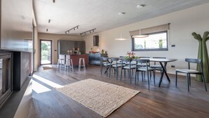 Une cuisine spacieuse dotée d’appareils électroménagers modernes, un coin repas avec une grande table et des chaises, et une vue sur l’extérieur par une fenêtre.