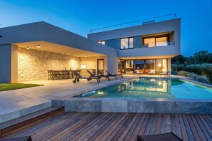 A modern house with a swimming pool, outdoor seating, and a stone wall. - Luxurious pool villa, 5 minutes walk from the beach (Banjole)
