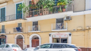 Un immeuble à la façade jaune, doté de nombreux balcons ornés de plantes et portant une enseigne indiquant « Associazione Italiana ».