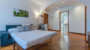 A bedroom with a bed, bedside table, lamp, and a painting on the wall.