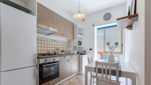 A modern kitchen with a dining area, featuring a stove, oven, microwave, and white cabinetry.