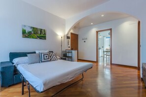 A bedroom with a bed, bedside table, lamp, and a painting on the wall.