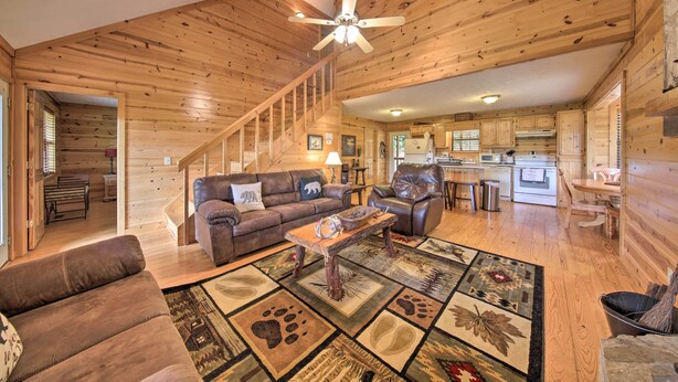 A spacious living room with a wooden ceiling, a sofa, a coffee table, and a rug with animal prints. - Rustic Young Harris Cabin w/ Fire Pit & Views (Young Harris)