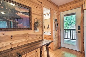 A wooden interior with a bench, a door leading outside, and a bathroom visible through an open door.