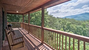 A wooden deck with benches and a railing overlooking a forested landscape with mountains in the distance. - Rustic Young Harris Cabin w/ Fire Pit & Views (Young Harris)