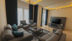 A modern living room with a sofa set, a coffee table, and a TV. - Princely Suites (Istanbul)