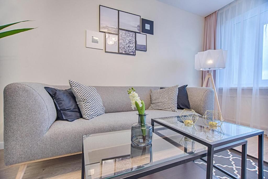 A modern living room with a grey sofa, a glass coffee table, and a floor lamp.