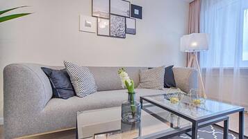 A modern living room with a grey sofa, a glass coffee table, and a floor lamp.
