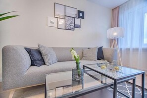 A modern living room with a grey sofa, a glass coffee table, and a floor lamp. - Princely Suites (Istanbul)