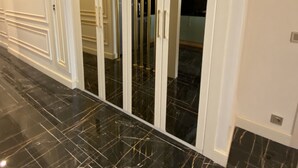 A hallway with a black marble floor, white walls, and a white door with gold handles. - Princely Suites (Istanbul)