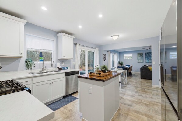 A modern kitchen with white cabinets, a central island, and a dining area with a table and chairs.