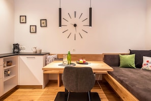 A modern kitchen with a wooden table, a black chair, and a sofa with cushions. - Luislhof Farm - Holiday Apartment Herbae with Mountain View, Terrace & Wi-Fi (Cornaiano)